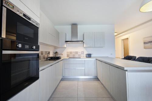 a kitchen with white cabinets and a black appliance at Spacious 2BD Apartment with Large Front Balcony & Country Views - Close to Sea in St Paul's Bay