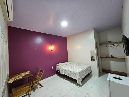 a room with a bed and a purple wall at Casa do Ivo Pousadas - Vip Alter in Alter do Chao