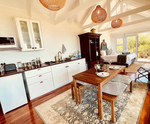 Una sala de estar con una mesa y una cocina. en Sea Views, Hikes & Tranquility Clifftop Cabin, en Plettenberg Bay