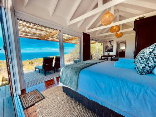 Un dormitorio con una cama y vista al mar. en Sea Views, Hikes & Tranquility Clifftop Cabin, en Plettenberg Bay