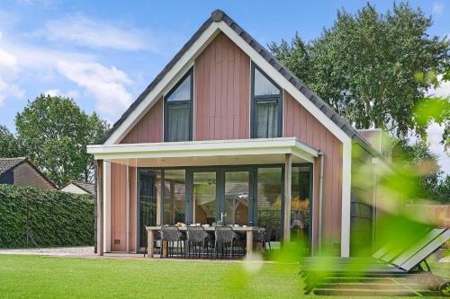 a house with a dining table in front of it at Villa Mastlo 2x 10 persons Ouddorp large garden, 1500 meters to the dunes and beach with 2 jacuzzi's - not for companies in Ouddorp