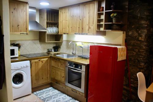 a kitchen with wooden cabinets and a red refrigerator at Apartament Cal Barracaire in Vilallonga de Ter
