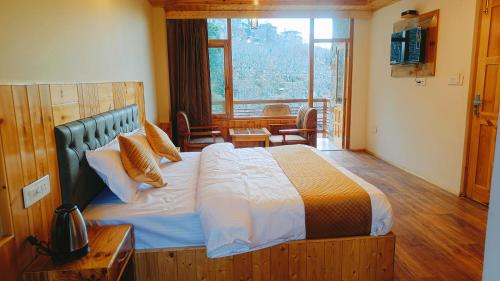 a bedroom with a large bed and a large window at Hotel Nayra in Manāli