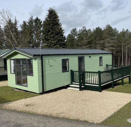 a green tiny house with a wooden porch at Slaley Forest Caravan petfriendly Retreat sleeps 6 in Hexham