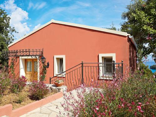a red house with a balcony and flowers at Grecotel LUXME Daphnila Bay in Dassia