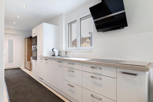 a kitchen with white cabinets and a tv on the wall at Ferienwohnung König in Lustenau