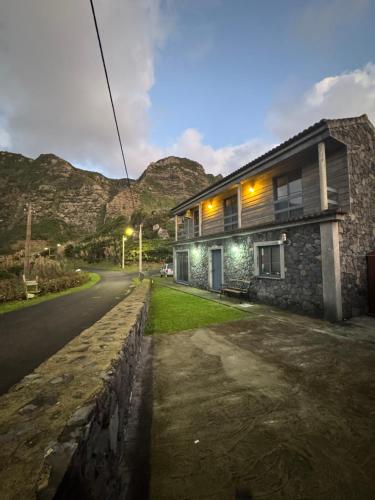 a house on a street with mountains in the background at Cantinho da Fajã in Faja Grande