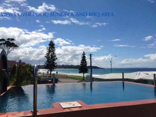 a swimming pool with a view of the ocean at Beach House Mollymook in Mollymook