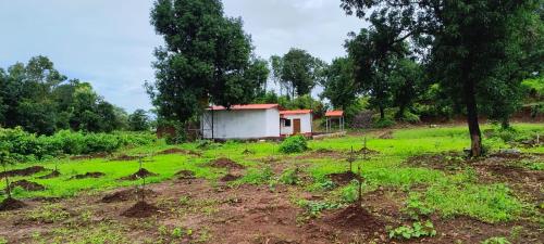 a small house in the middle of a field at Kittu's Farm in Murbād