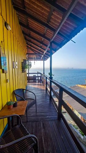 a wooden deck with chairs and a table and the ocean at Pousada Vida Simples in São Francisco do Sul