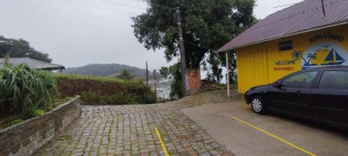 a car parked in front of a yellow building at Pousada Vida Simples in São Francisco do Sul