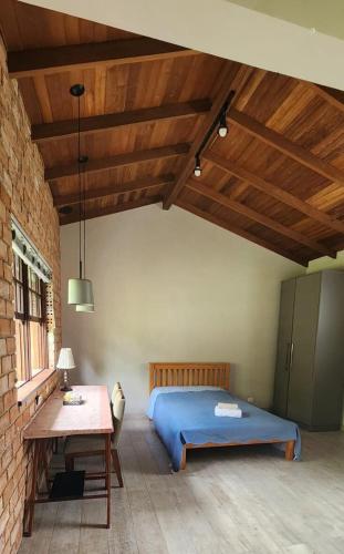 a bedroom with a blue bed and a table at Suíte Parque Barigui in Curitiba