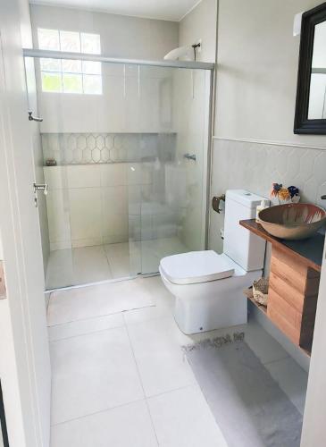 a bathroom with a toilet and a glass shower at Suíte Parque Barigui in Curitiba