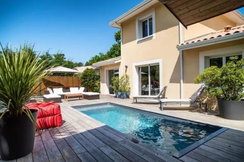 une piscine devant une maison dans l'établissement Villa au charme familial avec belle terrasse et piscine chauffée, à La Teste-de-Buch