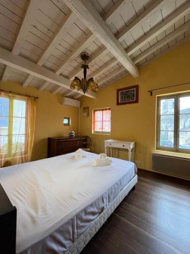 une chambre avec un grand lit blanc et deux fenêtres dans l'établissement La petite Major Arles centre, à Arles