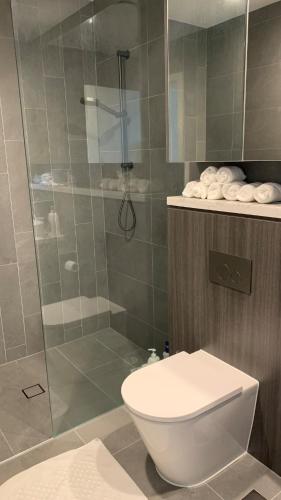 a bathroom with a toilet and a glass shower at The Podium 2B2B - 50mtr to ACCOR in Sydney