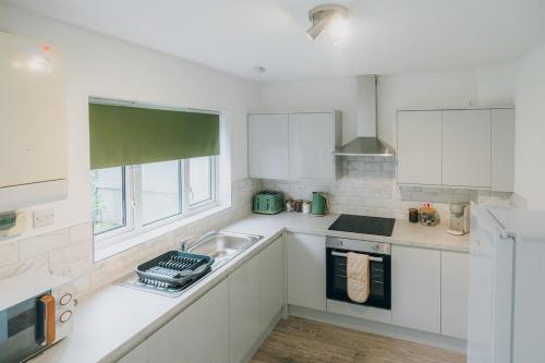 a white kitchen with a sink and a window at The Bay Hideaway - Lovely 2bd house - up to 6 people in Cardiff
