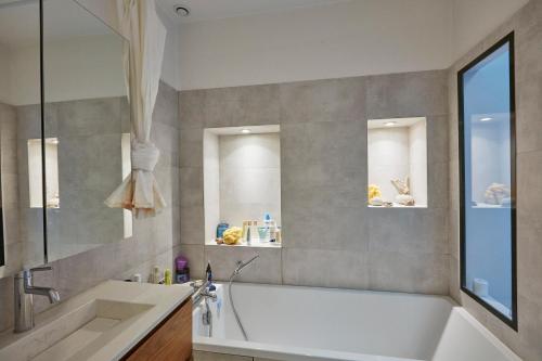 une salle de bain avec une baignoire blanche et un lavabo dans l'établissement Chez Julie - République, à Paris