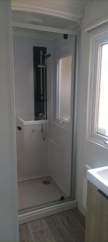 une douche dans une salle de bain avec une porte vitrée dans l'établissement camping les oyats, à Seignosse