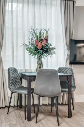 a vase of flowers sitting on a table with chairs at Cleveland Residences Bloomsbury in London