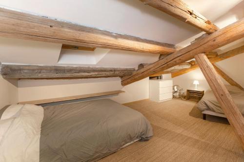 - une chambre mansardée avec un lit et des poutres apparentes dans l'établissement 3 clés Avignon centre, à Avignon