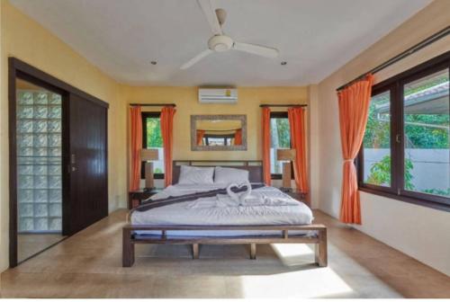 a bedroom with a large bed with orange curtains at Baan Tropicana in Mae Nam