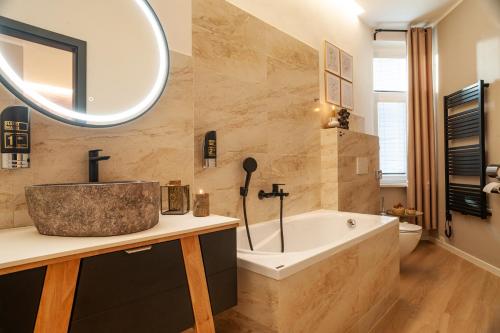 a bathroom with a tub and a sink and a mirror at STING Boutique Apartments in Ostrava