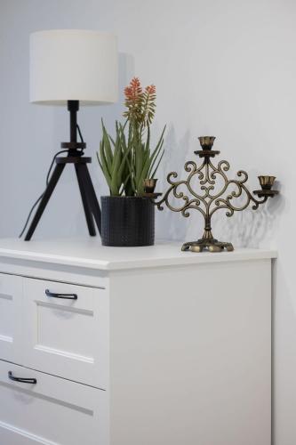 a white dresser with a lamp and plants on it at Wyjątkowy Apartament dla 4 osób by Noclegi Renters in Pruszków