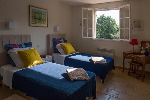 - une chambre dotée de 2 lits avec des draps bleus et jaunes dans l'établissement Villa Fontane, à La Garde-Freinet