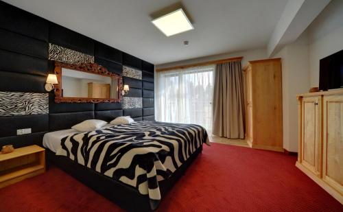 a zebra themed bedroom with a bed and a mirror at Hotel SZKLARSKA PORĘBA in Szklarska Poręba