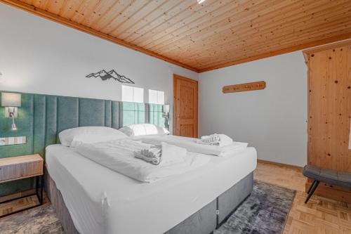 a large white bed in a bedroom with a wooden ceiling at Appartements Spitzegel in Hermagor