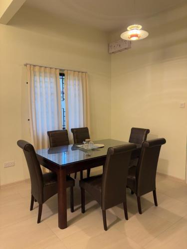 Una mesa de comedor con sillas negras y una ventana. en Blossom Hill homestay, en Kuantan