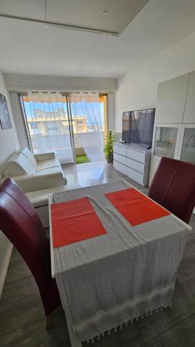 Cette chambre dispose d'une table, d'un canapé et d'une télévision. dans l'établissement Charmant studio avec parking, à Cagnes-sur-Mer