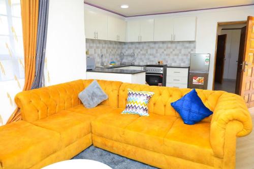 an orange couch in a kitchen with pillows on it at Christabell in Kisii