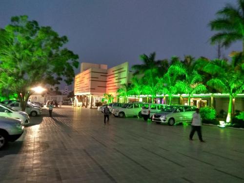 a parking lot with cars parked in front of a building at Pushpak Resort in Shirdi
