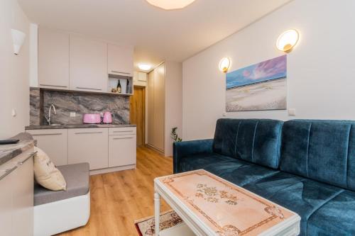 ein Wohnzimmer mit einer blauen Couch und einer Küche in der Unterkunft Apartament Capri z widokiem na morze- Krynica Morska in Krynica Morska