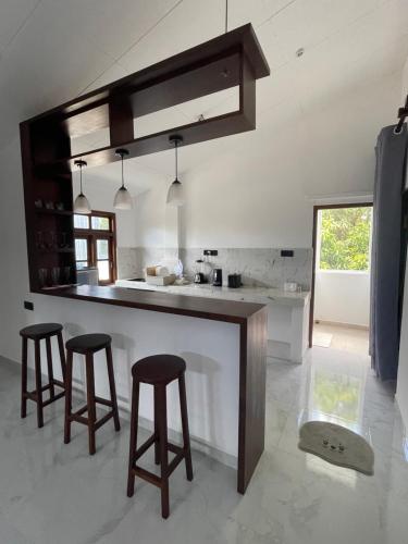 Una cocina con encimera y dos taburetes de bar. en Isi Villa, en Dikwella