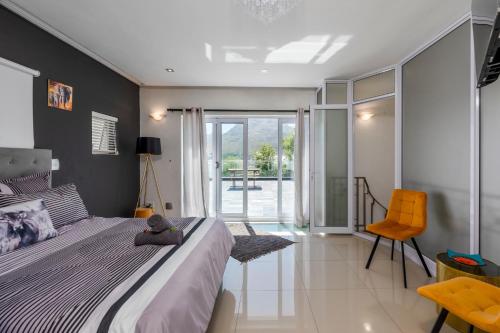 a bedroom with a large bed and a chair at Bed and Breakfast Villa Livadia in Cape Town