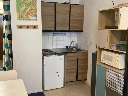 une petite cuisine avec un réfrigérateur et un micro-ondes dans l'établissement Studio cosy au 6e étage avec accès aux pistes - Le Pleynet - FR-1-557A-47, à La Ferrière