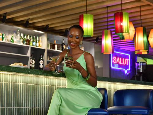 阿比让Ibis Styles Abidjan Marcory的坐在酒吧里看着手机的女人
