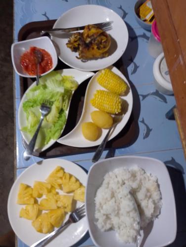 a table topped with plates of food with rice and vegetables at Naca Homestay in Manado