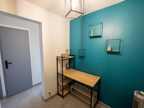 Cette chambre est dotée d'un mur bleu avec une table en bois. dans l'établissement Bel appartement 1 chambre, parking, wifi, climatisation - FR-1-723-132, au Cap d'Agde