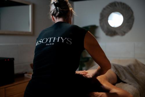 a woman sitting on a bed with her back to the camera at Keystone Hôtel & Spa in Lyon
