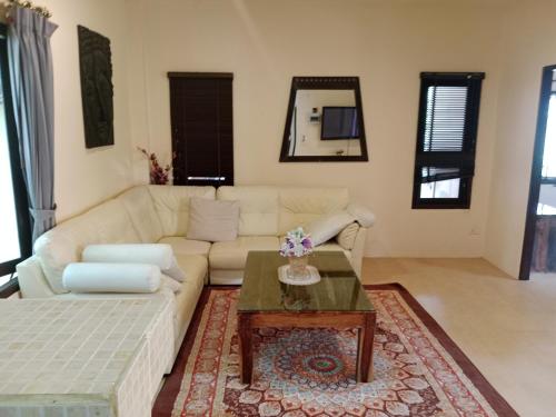 a living room with a white couch and a coffee table at Baan Tropicana in Mae Nam