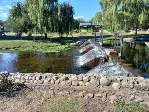a river with a stone wall and a waterfall at Cabaña El Chaparral Villa Dolores, Traslasierra 4 in Villa Dolores