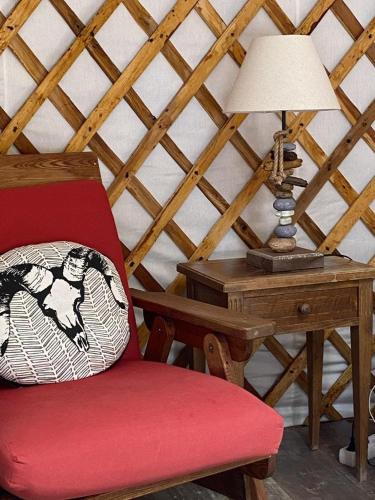 a red chair sitting next to a desk with a lamp at Yourte mongole in Champfromier