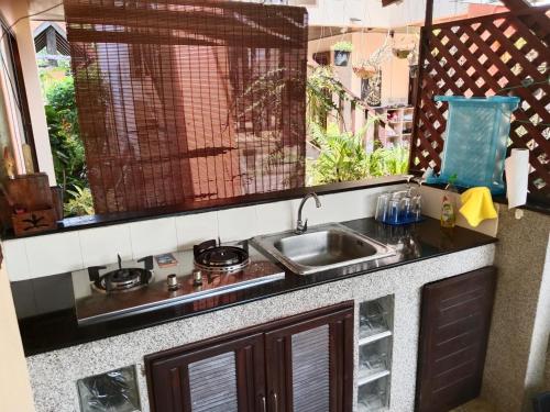 a kitchen counter with a sink and a window at Baan Tropicana in Mae Nam
