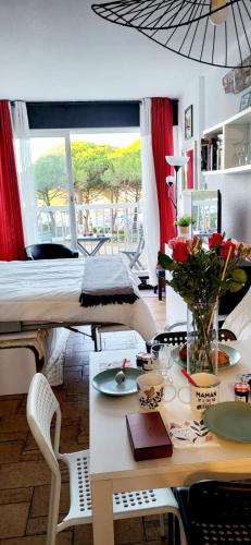 Cette chambre comprend un lit et une table fleurie. dans l'établissement La Croisière Nice view renovated studio air-conditioned parking balco, au Grau-du-Roi