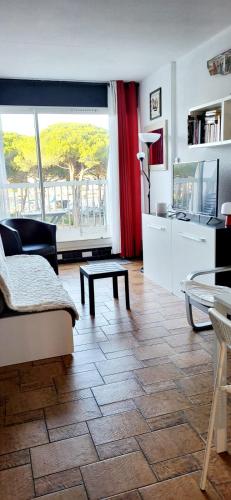 un salon avec une grande fenêtre et une table dans l'établissement La Croisière Nice view renovated studio air-conditioned parking balco, au Grau-du-Roi