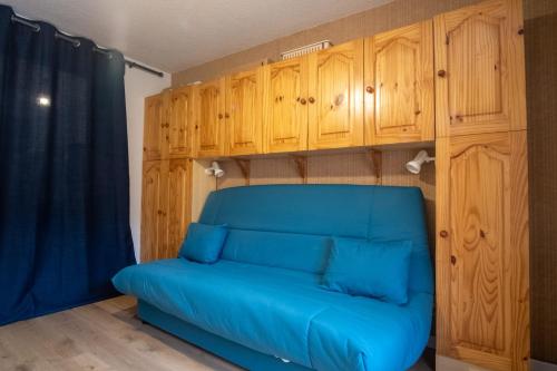 - un canapé bleu dans une pièce avec des placards en bois dans l'établissement Studio Belledonne - Welkeys, à Huez